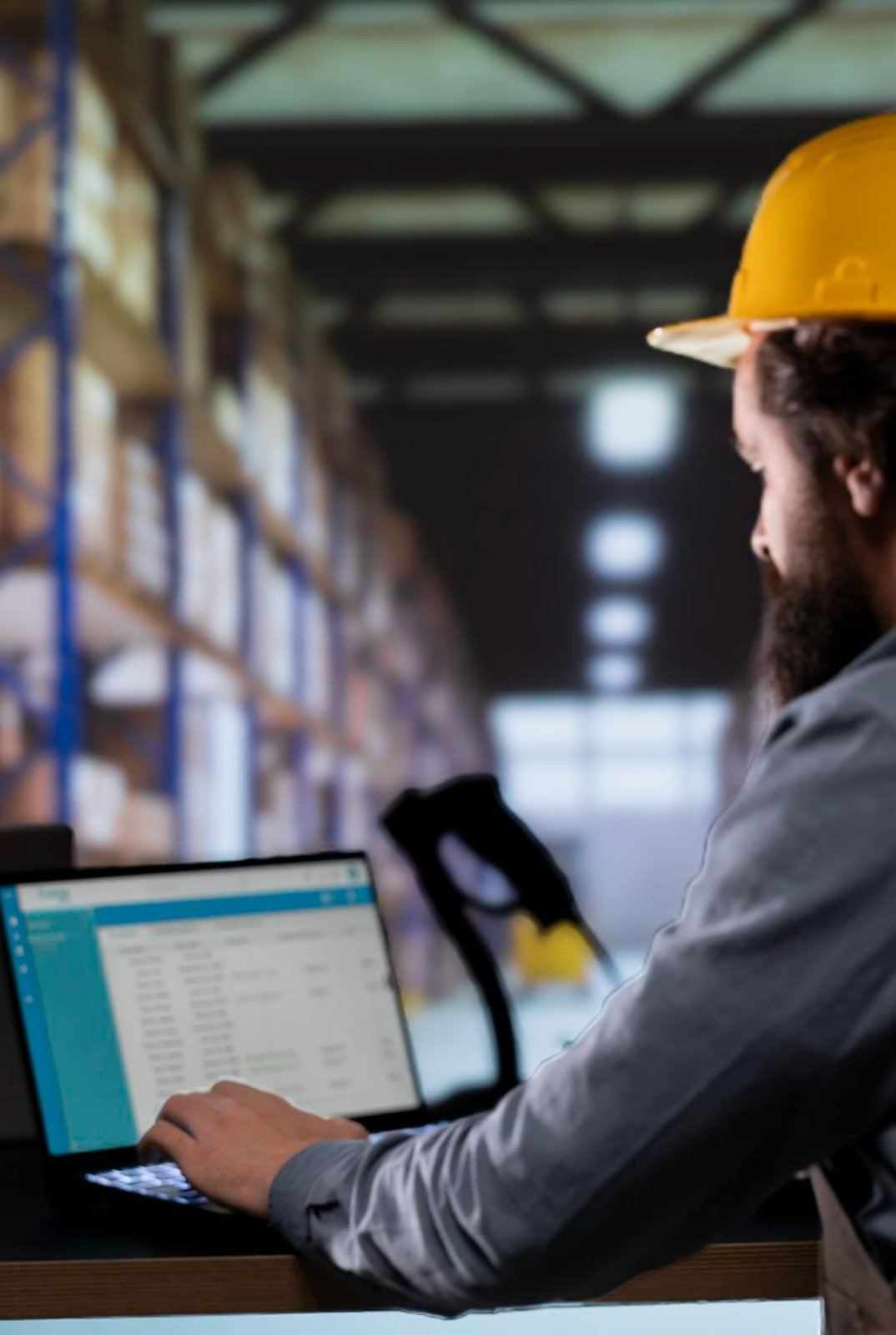 Warehouse worker in a hard hat working on a laptop